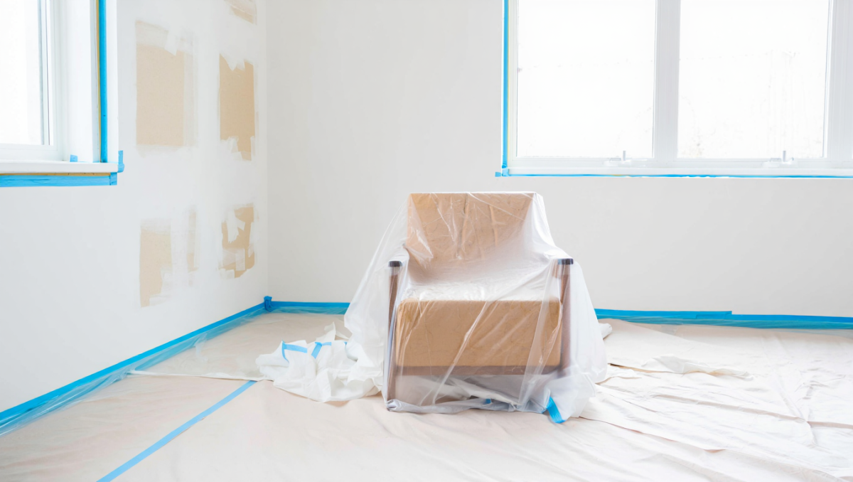 Chambre impeccablement préparée avant peinture : sol protégé, ruban de masquage posé, murs réparés.