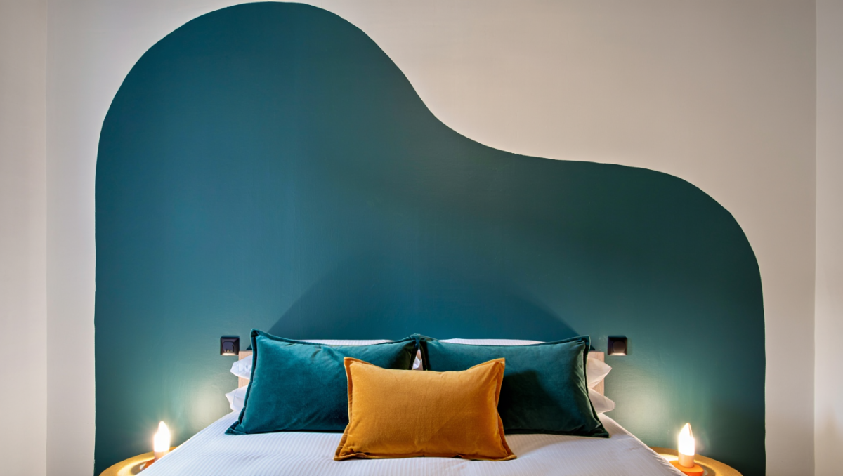 Chambre design avec une tête de lit originale créée grâce à une forme géométrique peinte sur le mur.